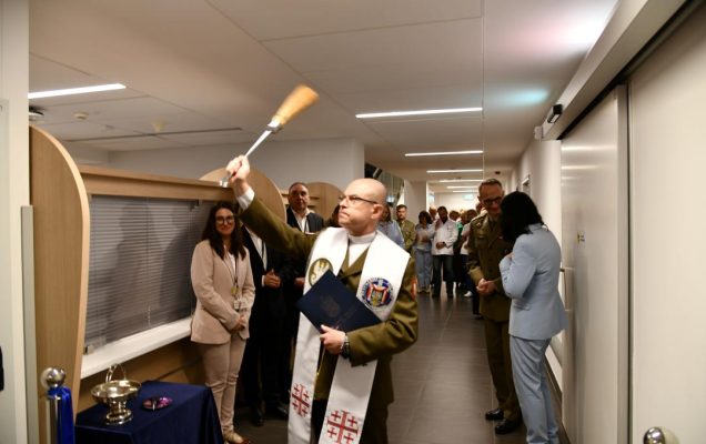 Kapelan wojskowy z kropidłem święci nowe pomieszczenia.