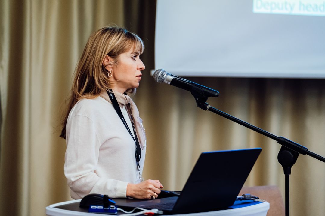 Katarzyna Gniadek przy mównicy, za nią ekran z wyświetlonym slajdem prezentacji.