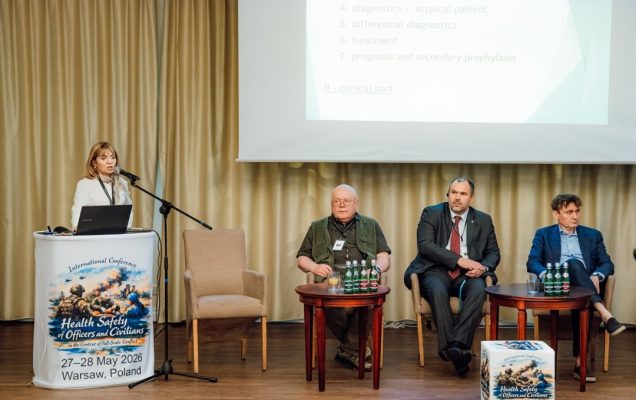 Katarzyna Gniadek przy mównicy, za nią ekran z wyświetlonym slajdem prezentacji oraz siedzący uczestnicy panelu konferencji.