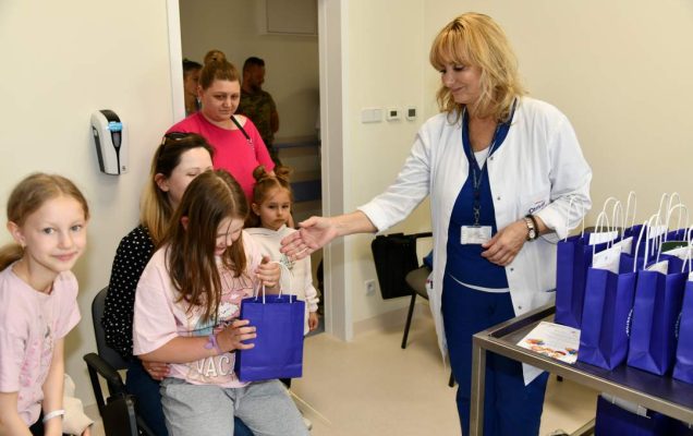Pracownicy kliniki przekazują dzieciom prezenty.