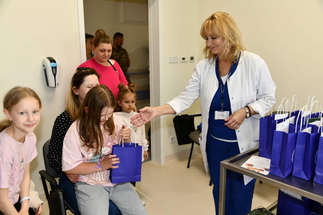 Pracownicy kliniki przekazują dzieciom prezenty.