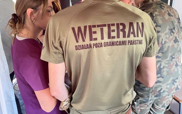 Weterani i pracownicy Centrum leczenia Weterana w namiocie wystawienniczym WIM. Mężczyzna w koszulce z napisem na plecach Weteran rozmawia z pracowniczką CLW.