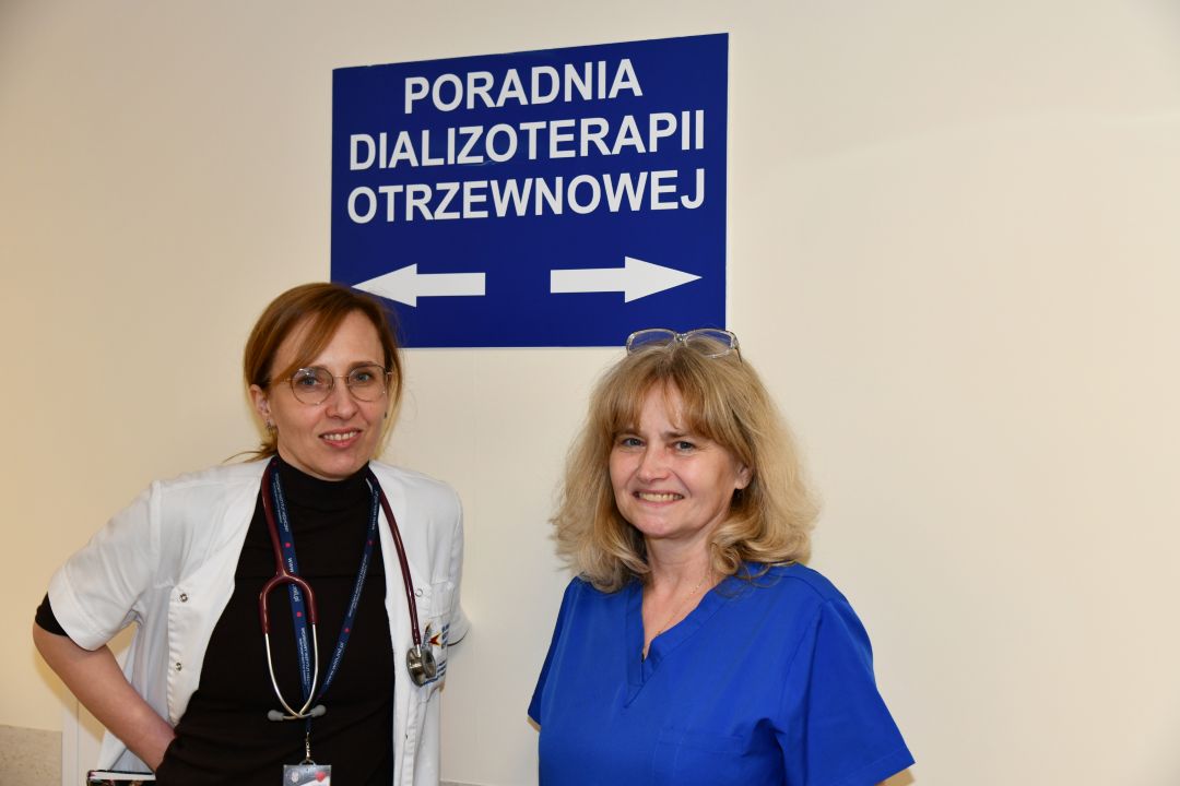 Pracowniczki Poradni Dializoterapii Otrzewnowej na korytarzu szpitalnym, za nimi tablica poradni.
