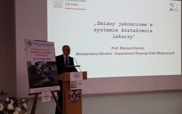Prof. Mariusz Klencki przy mównicy za jego plecami wyświetlony slajd prezentacji: Zmiany jakościowe w systemie kształcenia lekarzy.