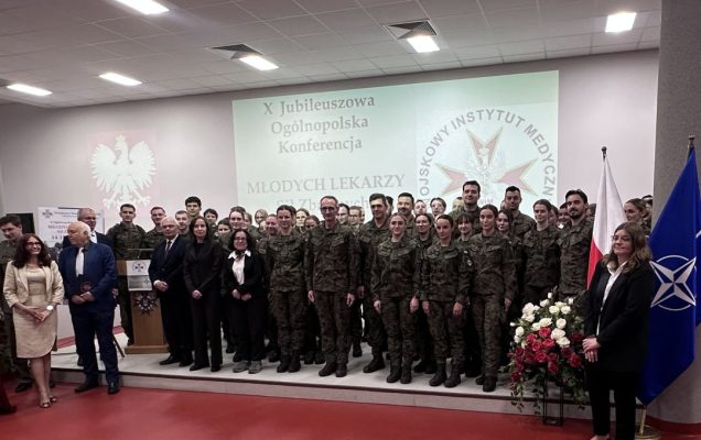 Zdjęcie grupowe uczestników konferencji, za nimi wyświetlony slajd z nazwą konferencji i logo WIM.