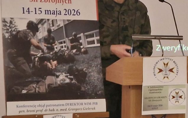 Dyrektor WIM przy mównicy, obok niego plakat konferencji,