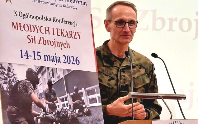 Dyrektor WIM przy mównicy, obok niego plakat konferencji,