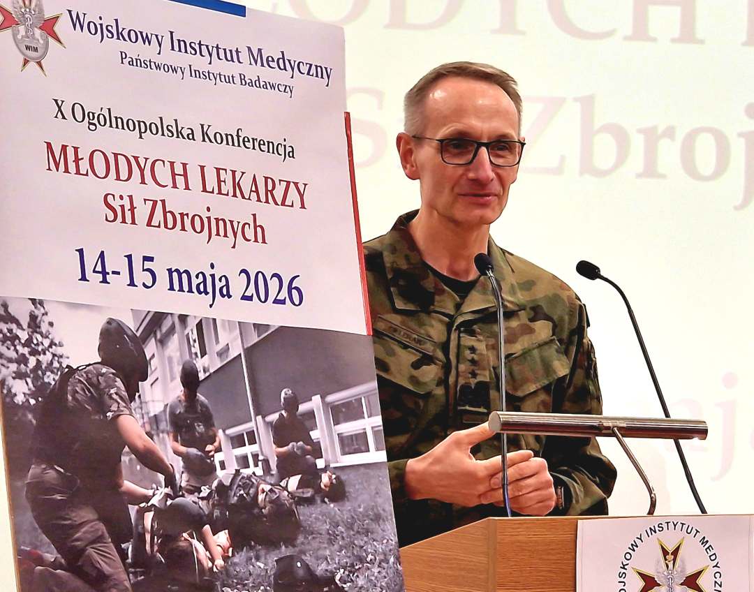 Dyrektor WIM przy mównicy, obok niego plakat konferencji,
