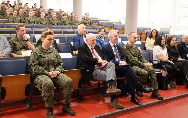 Siedzący słuchacze i goście na sali konferencyjnej.