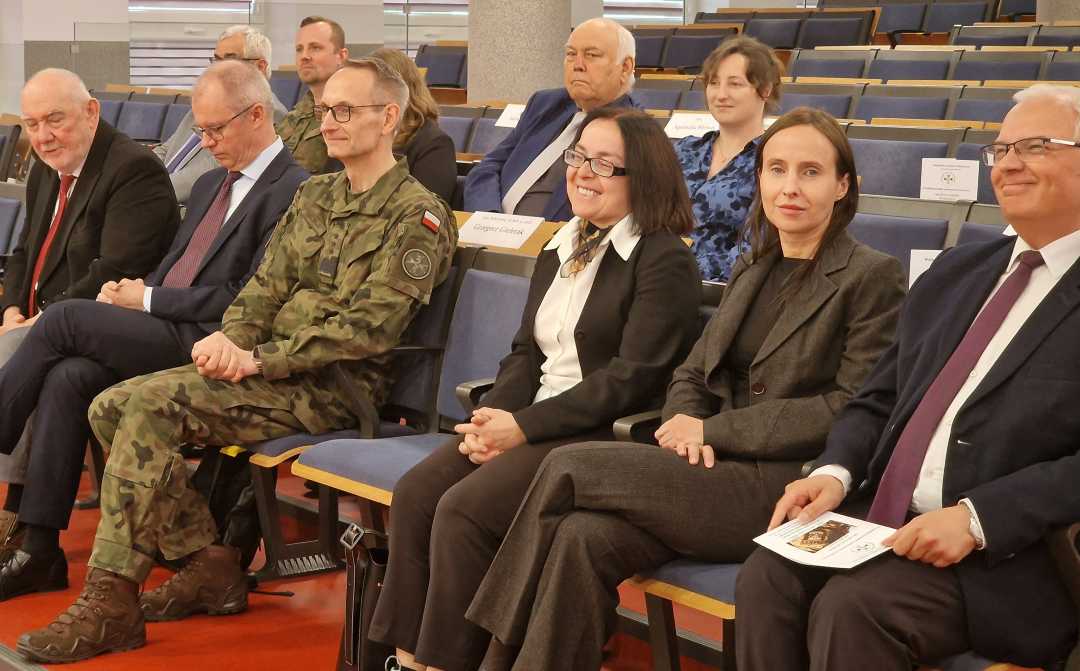 Siedzący goście - wykładowcy na sali konferencyjnej.