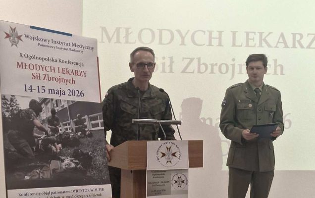 Dyrektor WIM przy mównicy podczas otwarcia konferencji, za jego plecami wyświetlony slajd z konferencji.
