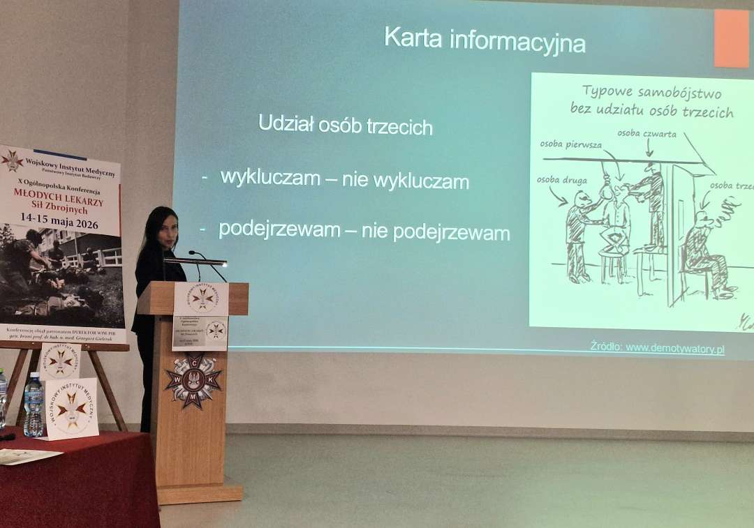 A. Michalska przy mównicy. Obok niej plakat konferencyjny, za jej plecami na wielkim ekranie wyświetlony slajd z prezentacji.