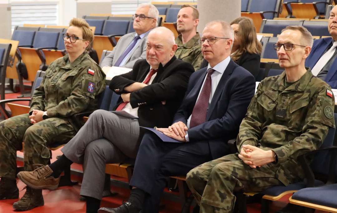 Siedzący wykładowcy goście na sali konferencyjnej.