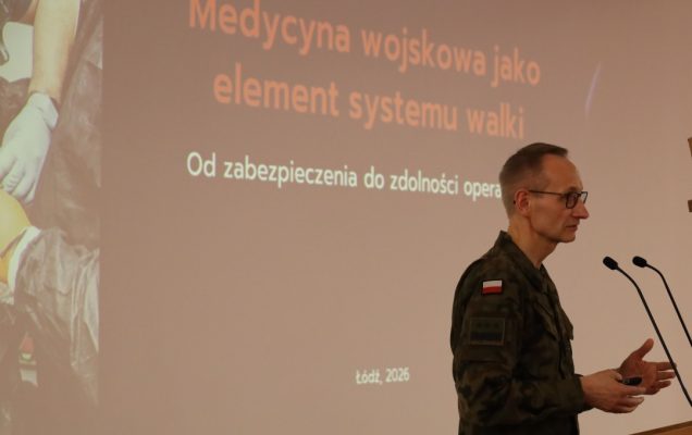 Dyrektor WIM przy mównicy, za jego plecami na ekranie slajd z prezentacji.