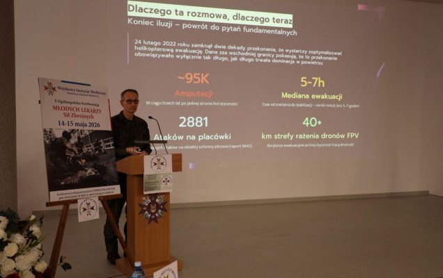 Dyrektor WIM przy mównicy, za jego plecami na ekranie slajd z prezentacji.