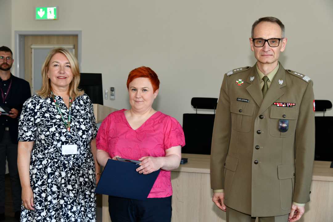 Grzegorz Gielerak i Marta Maciążek pozują z absolwentką trzymającą dyplom w rękach.