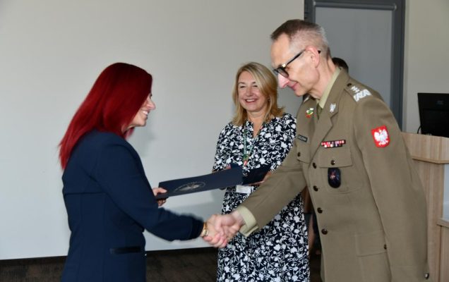 Grzegorz Gielerak ściska dłoń absolwentce odbierającej dyplom, obok stoi uśmiechnięta Marta Maciążek.