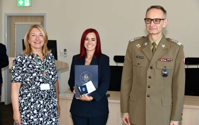 Grzegorz Gielerak i Marta Maciążek pozują z absolwentką stojącą pomiędzy nimi. Kobieta trzyma w rękach dyplom.