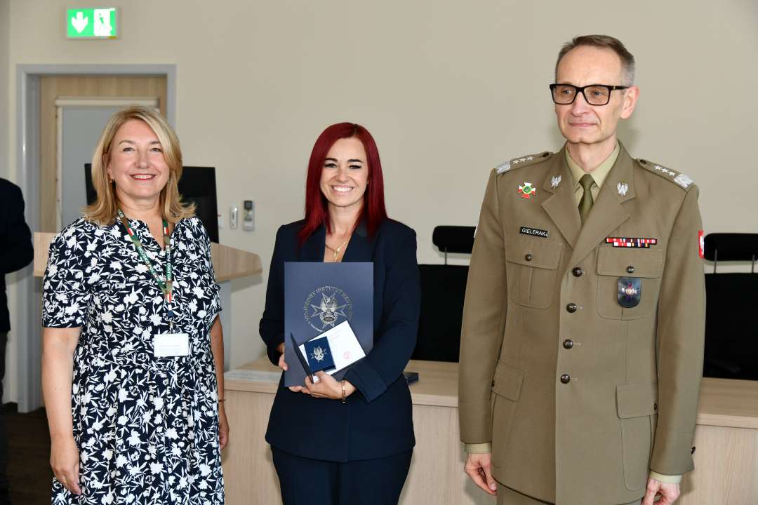 Grzegorz Gielerak i Marta Maciążek pozują z absolwentką stojącą pomiędzy nimi. Kobieta trzyma w rękach dyplom.