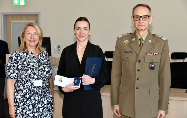 Grzegorz Gielerak i Marta Maciążek pozują z absolwentką stojącą pomiędzy nimi. Kobieta trzyma w rękach dyplom.