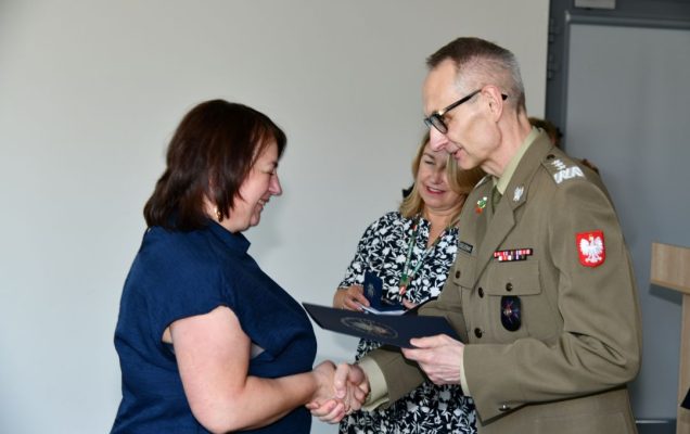 Grzegorz Gielerak ściska dłoń absolwentce odbierającej dyplom, obok stoi uśmiechnięta Marta Maciążek.