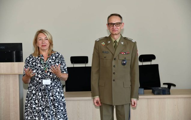 Marta Maciążek podczas przemówienia, obok stoi Grzegorz Gielerak ubrany w mundur wojskowy.