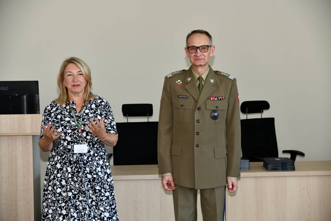 Marta Maciążek podczas przemówienia, obok stoi Grzegorz Gielerak ubrany w mundur wojskowy.