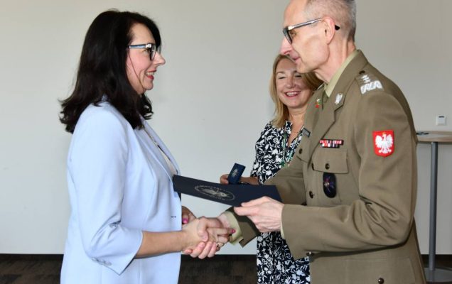 Grzegorz Gielerak ściska dłoń absolwentce odbierającej dyplom, obok stoi uśmiechnięta Marta Maciążek.