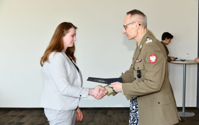Grzegorz Gielerak ściska dłoń absolwentce i wręcza dyplom, obok stoi uśmiechnięta Marta Maciążek.