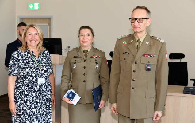 Grzegorz Gielerak i Marta Maciążek pozują z absolwentką w mundur wojskowy stojącą pomiędzy nimi. Kobieta trzyma w rękach dyplom.