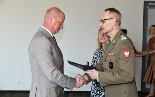 Grzegorz Gielerak ściska dłoń absolwentowi odbierającemu dyplom, obok stoi uśmiechnięta Marta Maciążek.