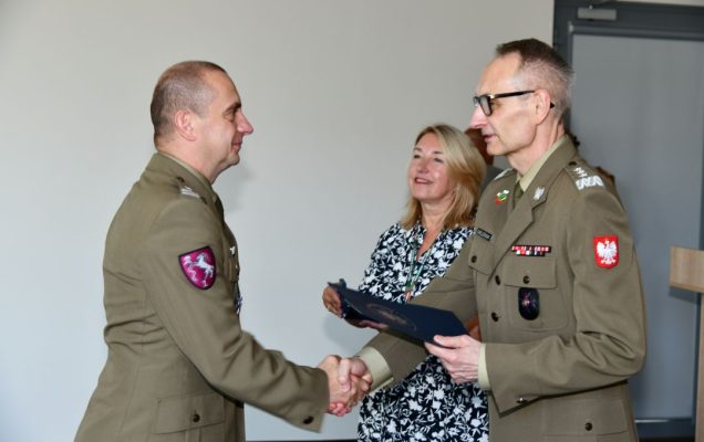 Grzegorz Gielerak ściska dłoń absolwentowi odbierającemu dyplom, obok stoi uśmiechnięta Marta Maciążek.