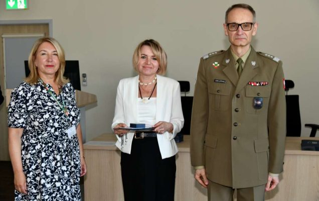 Grzegorz Gielerak i Marta Maciążek pozują z absolwentką stojącą pomiędzy nimi. Kobieta trzyma w rękach dyplom.