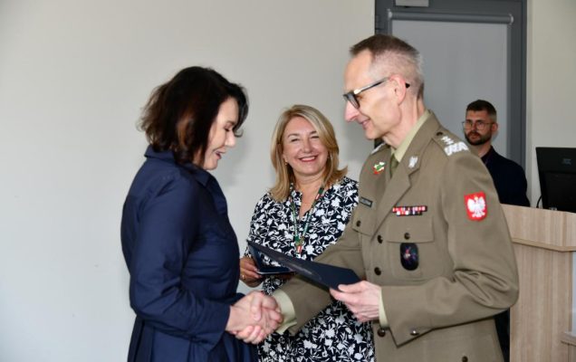 Grzegorz Gielerak ściska dłoń absolwentce odbierającej dyplom, obok stoi uśmiechnięta Marta Maciążek.