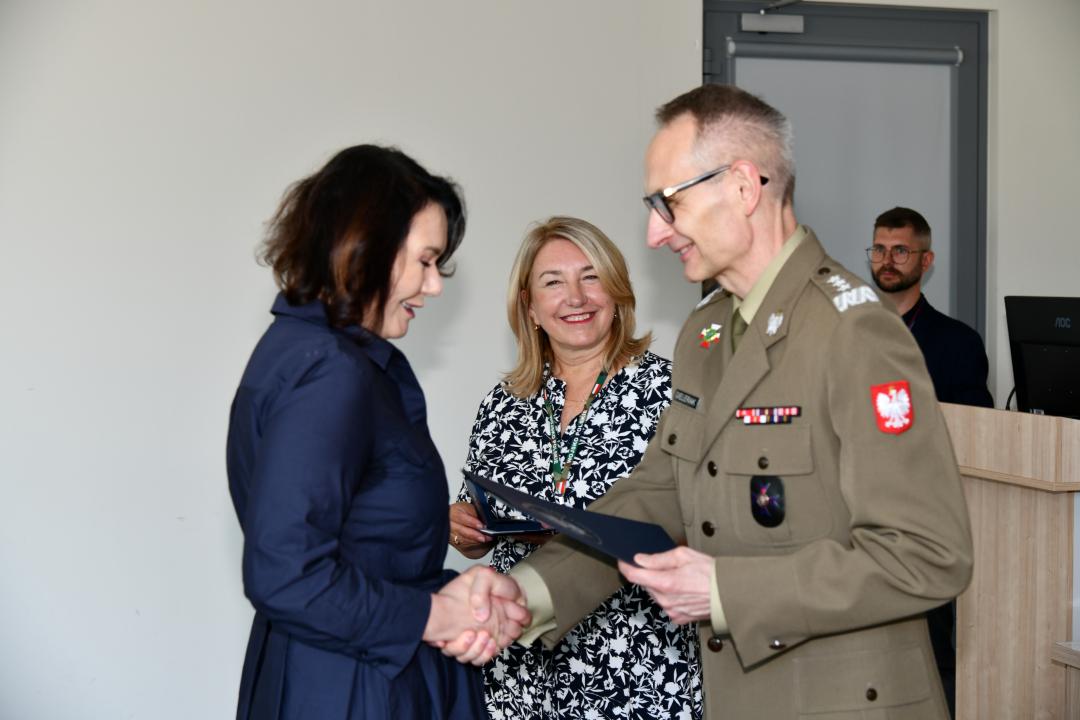 Grzegorz Gielerak ściska dłoń absolwentce odbierającej dyplom, obok stoi uśmiechnięta Marta Maciążek.