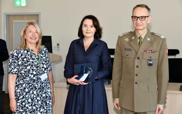Grzegorz Gielerak i Marta Maciążek pozują z absolwentką stojącą pomiędzy nimi. Kobieta trzyma w rękach dyplom.