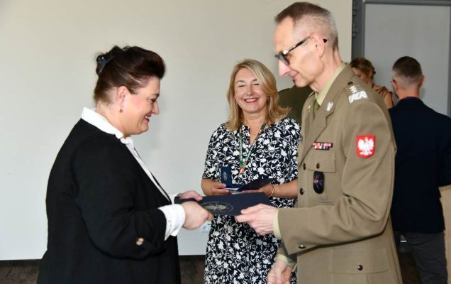 Grzegorz Gielerak ściska dłoń absolwentce odbierającej dyplom, obok stoi uśmiechnięta Marta Maciążek.