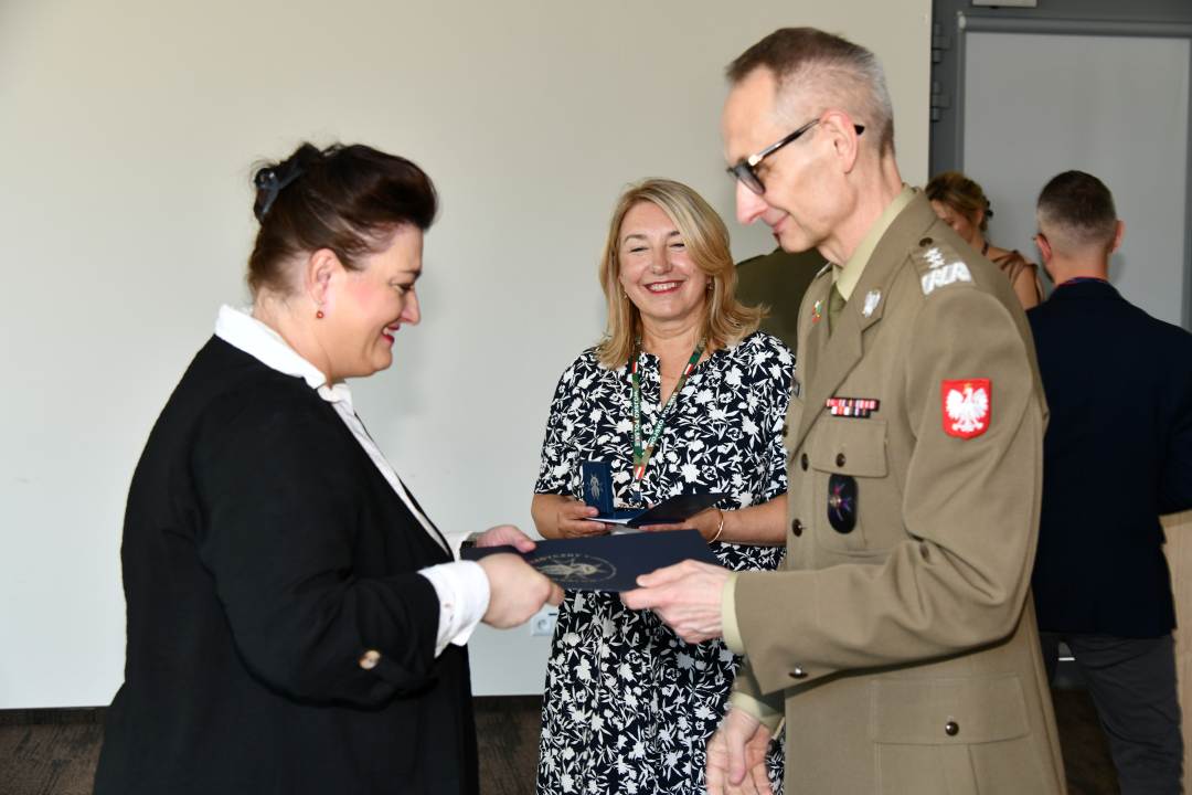 Grzegorz Gielerak ściska dłoń absolwentce odbierającej dyplom, obok stoi uśmiechnięta Marta Maciążek.