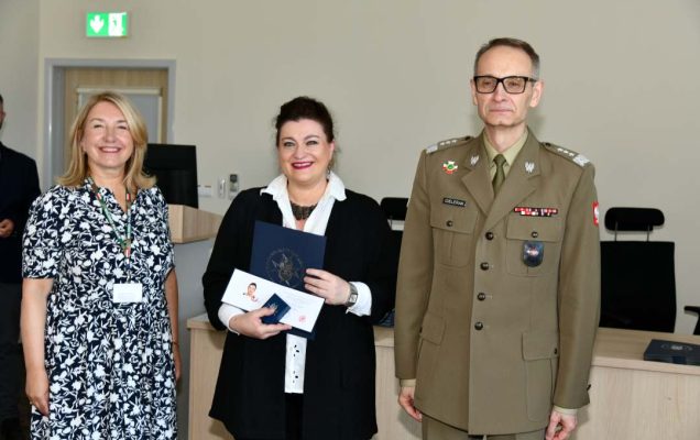 Grzegorz Gielerak i Marta Maciążek pozują z absolwentką stojącą pomiędzy nimi. Kobieta trzyma w rękach dyplom.