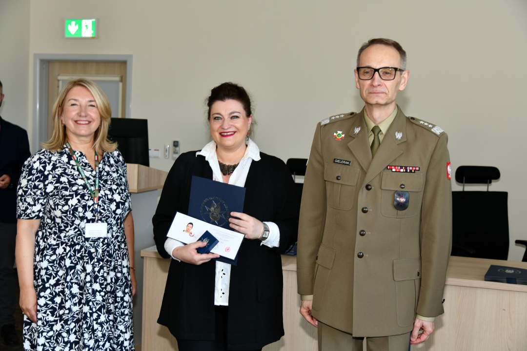 Grzegorz Gielerak i Marta Maciążek pozują z absolwentką stojącą pomiędzy nimi. Kobieta trzyma w rękach dyplom.