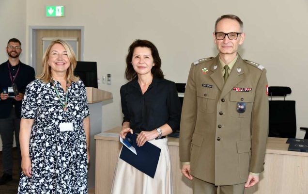 Grzegorz Gielerak i Marta Maciążek pozują z absolwentką stojącą pomiędzy nimi. Kobieta trzyma w rękach dyplom.