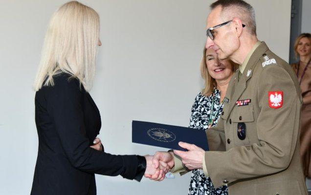 Grzegorz Gielerak ściska dłoń absolwentce odbierającej dyplom, obok stoi uśmiechnięta Marta Maciążek.