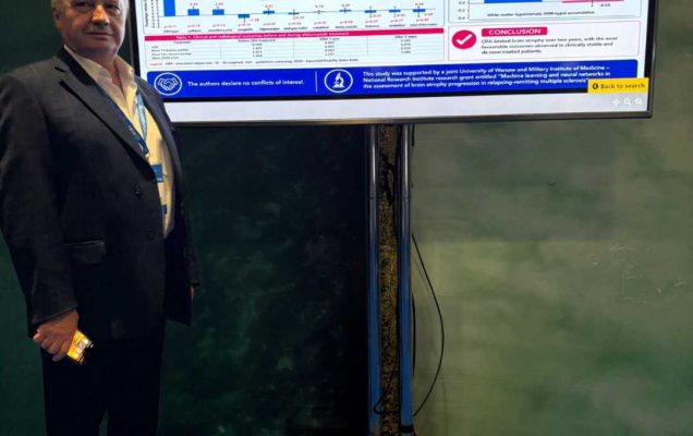 Mężczyzna w garniturze stoi obok dużego ekranu prezentującego plakat naukowy dotyczący wpływu ofatumumabu na zanik mózgu u pacjentów ze stwardnieniem rozsianym.