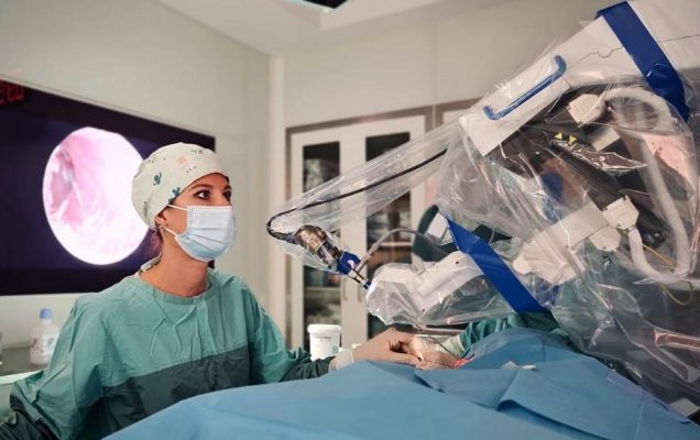 Chirurżka przy konsoli robota w trakcie operacji robotycznej.
